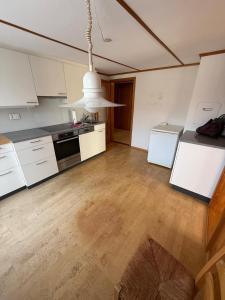 LaVida Wave Lakeside Haven am Thunersee & Alps في ليسيغن: مطبخ بدولاب أبيض وسقف أبيض