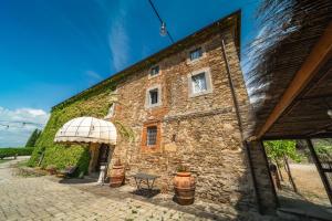 un vecchio edificio in pietra con tavolo e ombrellone di Santantimo Tuscany Inn ad Arezzo