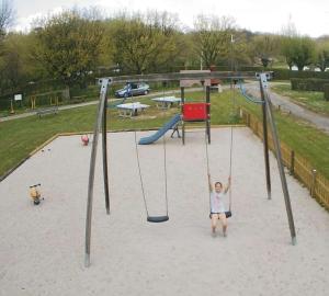 a little girl on a swing in a playground at ZEcamping 4 familial animaux acceptés avec piscine et soirées animées in Lons-le-Saunier