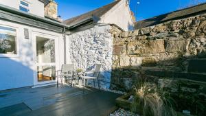 a patio with chairs and a stone wall at Rutherglen in Beaumaris