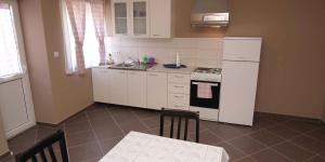 a kitchen with white appliances and a table and chairs at Federica A2+1 in Veli Lošinj