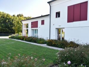 a white house with red doors and a yard at Domus Natura, un'oasi verde tra Padova e Venezia in Vigonza