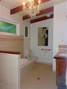 a bathroom with a tub and a toilet and a chandelier at Kuranda Ngorongoro Lodge in Kuranda