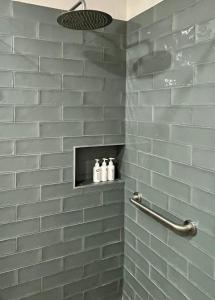 Una ducha de azulejos grises con tres botellas en un estante. en AtSupers Accommodation, en Jeffreys Bay