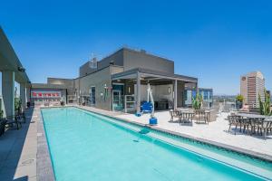 a swimming pool with tables and chairs and a building at Panoramic Studio-1BR-3BR, Pool, Gym, Parking, Patio, BBQ in Phoenix