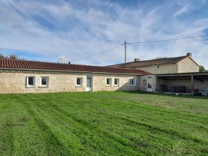 a building with a large grass field in front of it at La bergerie in Coussay