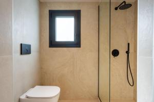 a bathroom with a shower with a toilet and a window at NAMA Suites in Hersonissos