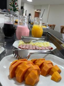 einen Tisch mit Teller mit Lebensmitteln auf einer Theke in der Unterkunft San Diego Suítes Manhuaçu in Manhuaçu