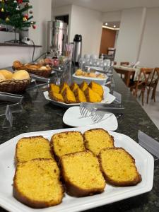 einen Tisch mit Brotplatten und anderen Lebensmitteln in der Unterkunft San Diego Suítes Manhuaçu in Manhuaçu + 27 Fotos