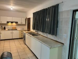 a kitchen with white cabinets and a counter top at Shelly Bay House in Margate