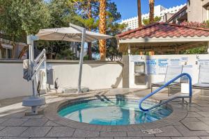 una piccola piscina con un ombrellone e uno scivolo d'acqua di Desert Rose Resort a Las Vegas