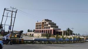 a large white building in front of a parking lot at Lords Swastik Studio Kodinar in Kodīnar
