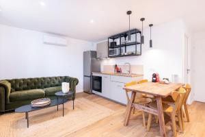 a living room with a green couch and a table at La Maison Bretzel & SPA Medipole - Climatisé in Villeurbanne