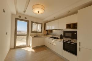 a kitchen with white cabinets and a large window at Luxury 2 Bedroom Apartment Menzah 9C Near the airport in Tunis