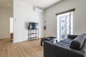 a living room with a couch and a tv at Downtown 1 Bedroom Apartment E - 150m from the Beach in Albufeira