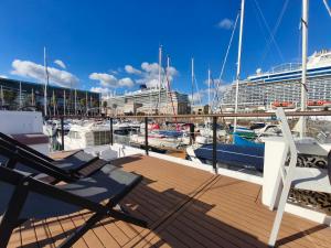 a deck with chairs and a cruise ship in a marina at Barco Different Charter - Experiencia Única en el Puerto Deportivo de Vigo in Vigo