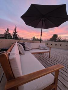 a couch sitting on a deck with an umbrella at על הגג במדבר in Mitzpe Ramon