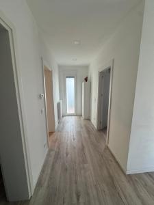 House 31 Plus في مونفالكوني: ممر فارغ بجدران بيضاء وارضيات خشبية