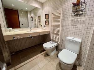 Un baño con inodoro, lavabo y espejo. en Apartamentos Valle de Inclés MIKKA, en Soldeu 24 fotos más