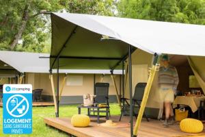 a man standing under a tent with a surfboard at ZEcamping 3 animaux acceptés piscine et restaurant in Saintes