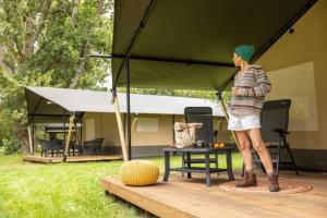 a woman standing inside of a green tent at ZEcamping 3 animaux acceptés piscine et restaurant in Saintes +7 photos