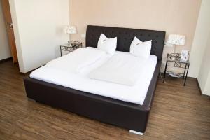 a large bed with white sheets and pillows at Hosser's Hotel Restaurant in Idar-Oberstein