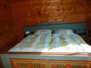 a bedroom with a bed with a wooden wall at Moaralmhütte in Görtschach