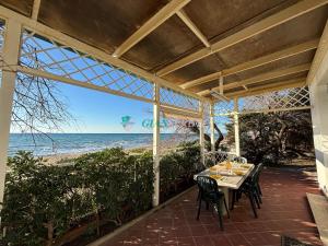 a patio with a table and chairs and the beach at Casabianca in San Vincenzo