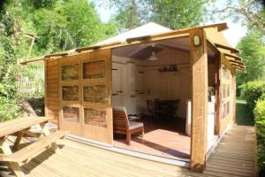 a small wooden shed with a bench and a table at ZEcamping 3 étoiles avec piscine bar et restaurant en bord de ruisseau in Belguiral