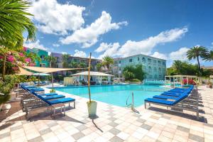 a swimming pool with blue lounge chairs and umbrellas at Ocean Point Beach Resort & Spa Adults Only in Saint Johnʼs