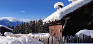 a house covered in snow with a fence at Reh's Wiesen Hütte in Luson