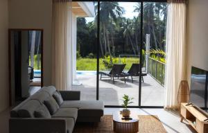 ein Wohnzimmer mit Couch und großem Fenster in der Unterkunft Modern Pool Villa Escape in Koh Phangan in Ko Phangan