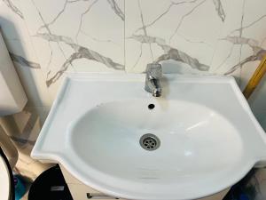 Apartamento Rua Rainha Ginga في لواندا: بالوعة بيضاء في الحمام بجدار من الرخام +صورة واحدة