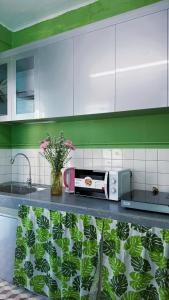 Cozy 2BR Retreat with Outdoor Living & Garden في دا نانغ: مطبخ فيه دواليب بيضاء و كونتر فيه ورد