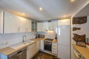 una cocina con armarios blancos y electrodomésticos blancos en Casa Los Morros, en Tazacorte