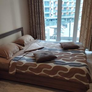 a bed in a bedroom with a large window at Бежевые апартаменты in Batumi