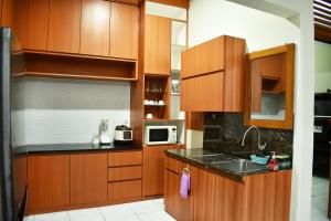 a kitchen with wooden cabinets and a microwave at Pondok Sukamanah Tasik in Tasikmalaya