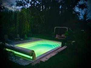 Una piscina con iluminación verde en un patio. en La Maison Labonnechose - Piscine chauffée - Calme - Jeux, en Notre-Dame-de-Fresnay 25 fotos más