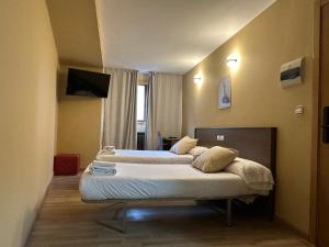 two beds sitting in a room with a window at Hotel Santa Catalina by Bossh Hotels! in A Coruña