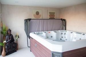 een badkuip in een badkamer met een standbeeld ernaast bij Dôme du levant in Holving +19 foto's