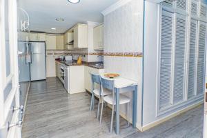una cucina con mobili bianchi, tavolo e sedie di Villa Daniela a Almería