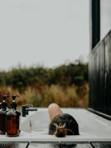 een vrouw die in een badkuip ligt met een fles zeep bij Alcor in Swynnerton +3 foto's