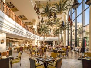 a restaurant with tables and chairs in a building at Sofitel Bahrain Zallaq Thalassa Sea & Spa in Manama