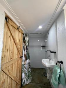 ein Badezimmer mit einer Schiebetür und einem Waschbecken in der Unterkunft Wooden Cottage for 5 Near Lake Naivasha, Elwai Visitor Centre in Heni Village