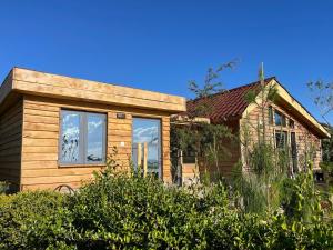 ein Holzhaus mit Fenstern und Büschen in der Unterkunft Wooden Cottage for 5 Near Lake Naivasha, Elwai Visitor Centre in Heni Village