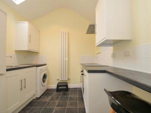 una cocina con gabinetes blancos y una lavadora y secadora en Violet's Rest, en Exeter