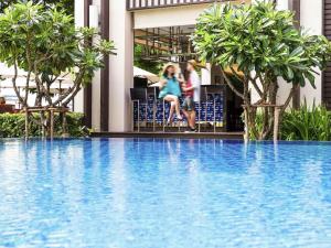 バンコクにあるイビス バンコク リバーサイドの二人の女の子がスイミングプールの横に座って座っている +44枚の写真