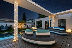 een terras met stoelen en 's nachts een zwembad bij Villa Boston luxury home with pool and Cali vibes in Le Grau-dʼAgde
