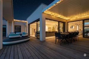 een huis met een houten terras met een eettafel bij Villa Boston luxury home with pool and Cali vibes in Le Grau-dʼAgde