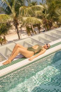 una donna sdraiata sul bordo di una piscina di Sana Tulum Beachfront Boutique Hotel a Tulum